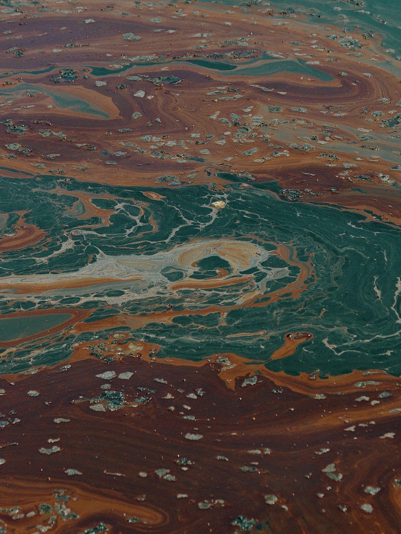 An iridescent sheen swirling across a dark water surface