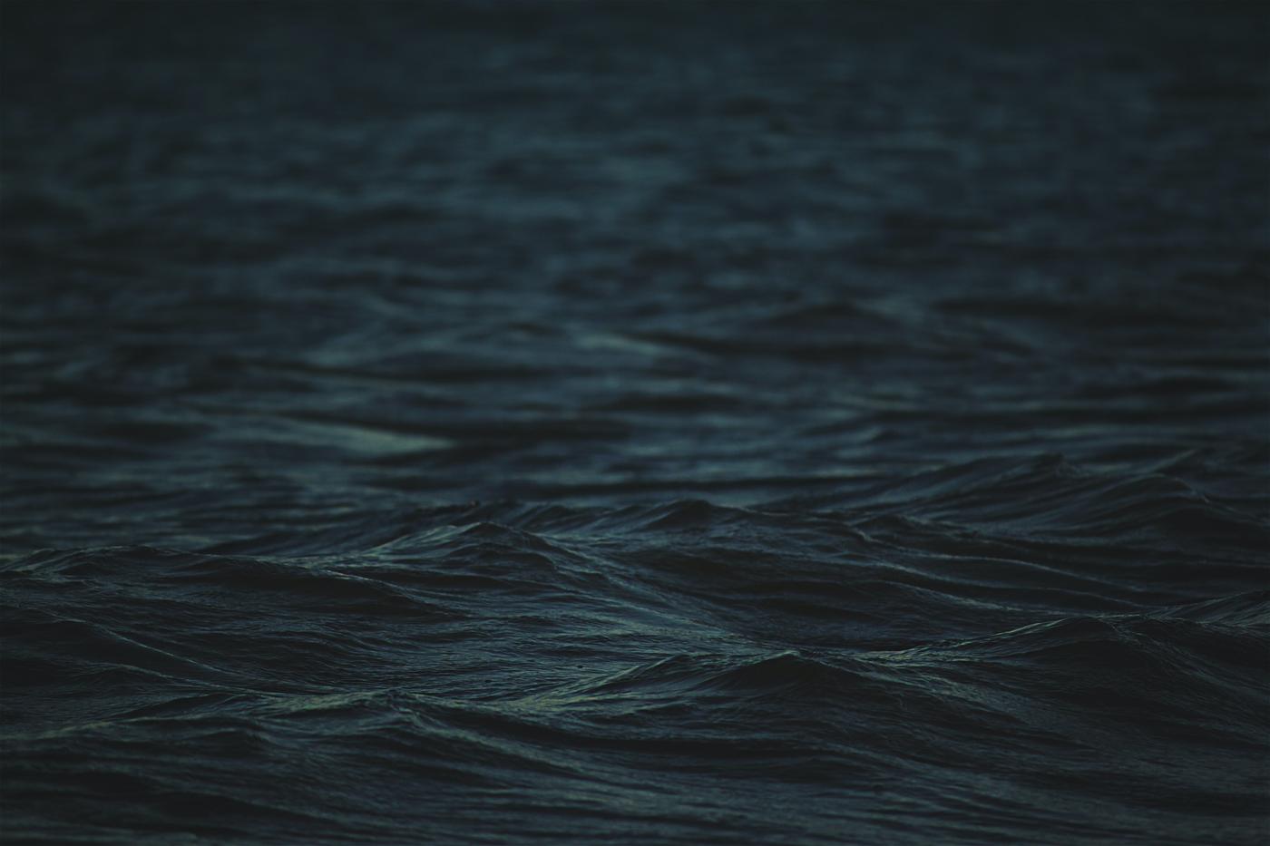 Dark water moving in long low swells under flat light